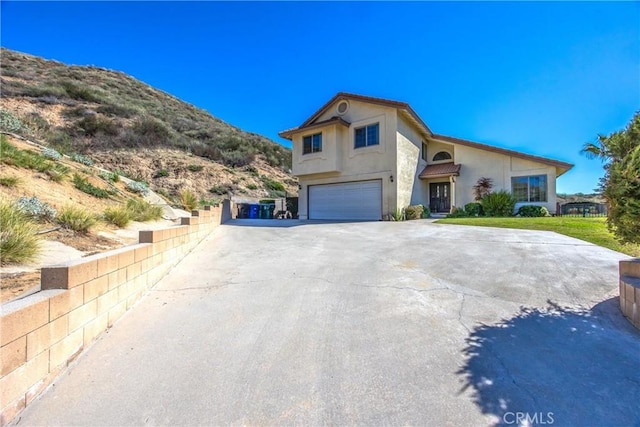 view of front facade with a garage, driveway, a mountain view, and stucco siding