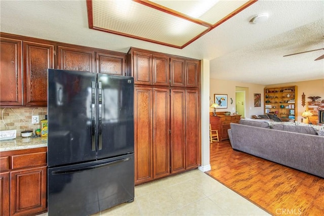 kitchen with a textured ceiling, a ceiling fan, open floor plan, backsplash, and freestanding refrigerator