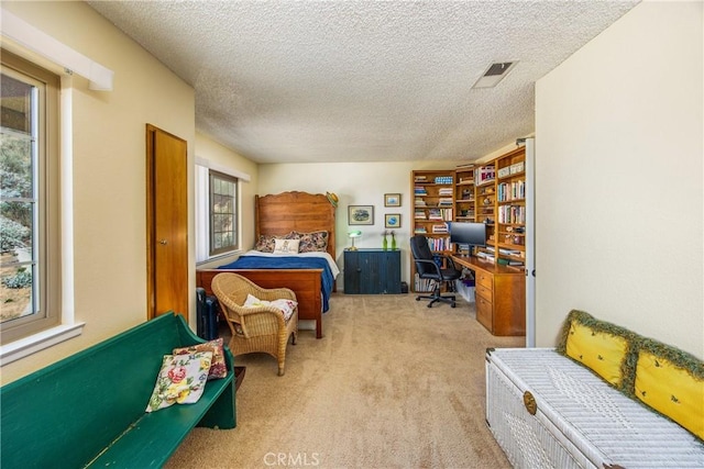 carpeted bedroom featuring a textured ceiling and visible vents