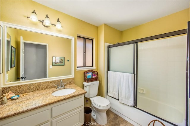 bathroom featuring combined bath / shower with glass door, tile patterned flooring, vanity, and toilet