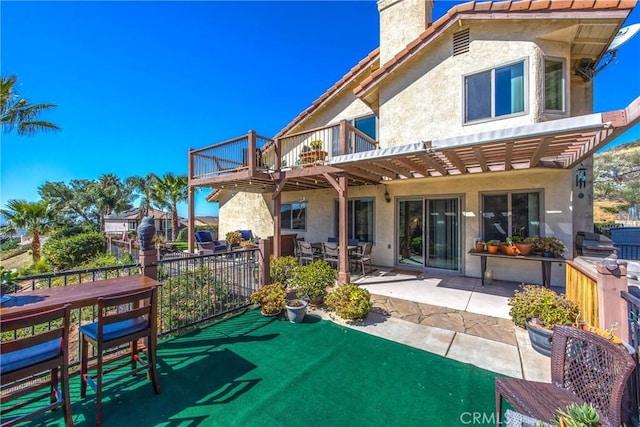 rear view of property featuring a patio area, a chimney, and stucco siding