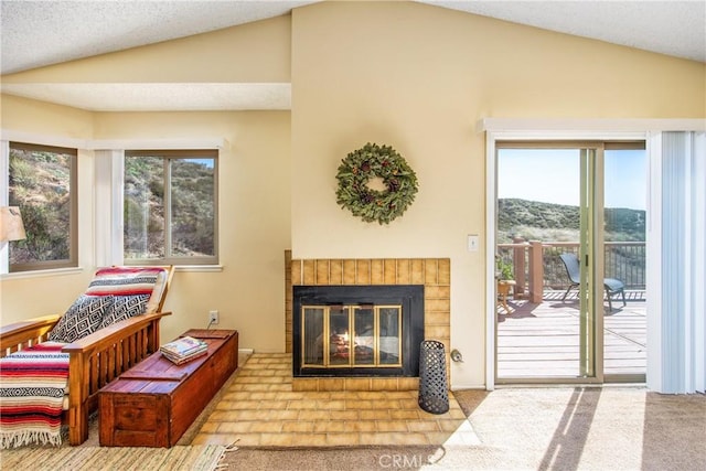 living area featuring vaulted ceiling, plenty of natural light, and a fireplace with flush hearth