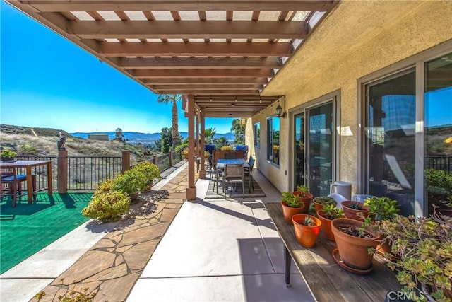 view of patio featuring outdoor dining space, a mountain view, fence, and a pergola