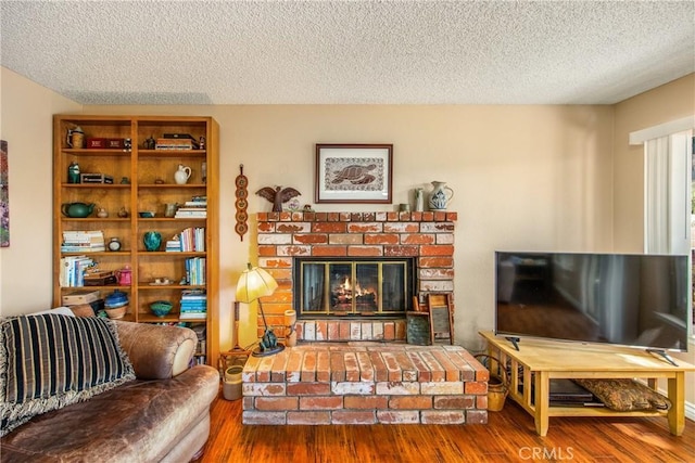 living area with a textured ceiling, a fireplace, and wood finished floors