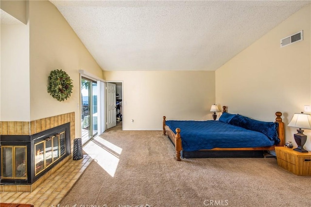 carpeted bedroom with lofted ceiling, a textured ceiling, a fireplace, visible vents, and access to exterior