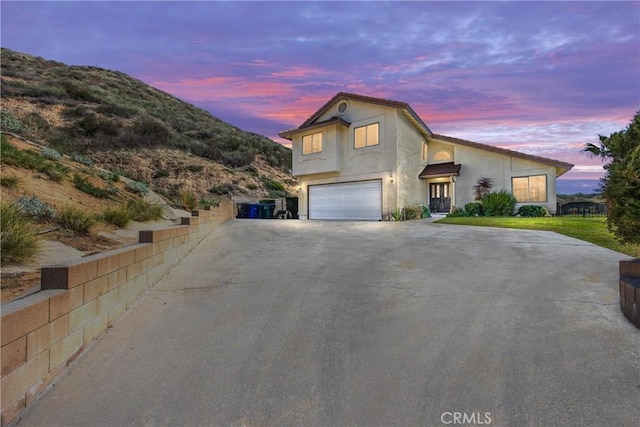 view of front of property with an attached garage, a mountain view, fence, concrete driveway, and stucco siding