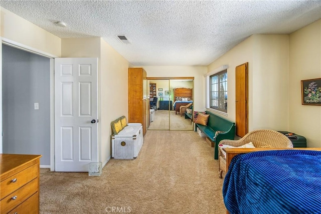 carpeted bedroom with a textured ceiling, visible vents, and a closet