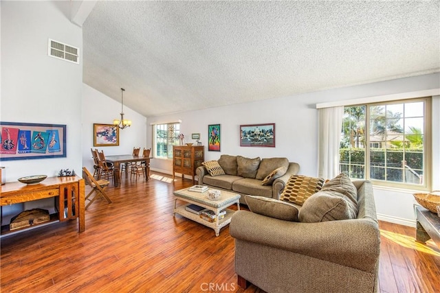 living area featuring vaulted ceiling, hardwood / wood-style flooring, a textured ceiling, and visible vents