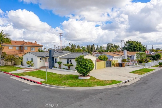 view of front facade with concrete driveway, a front yard, fence, and a residential view