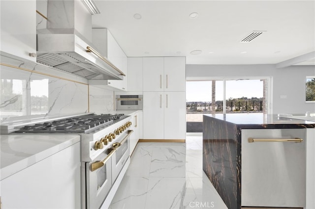 kitchen featuring visible vents, marble finish floor, appliances with stainless steel finishes, wall chimney range hood, and decorative backsplash