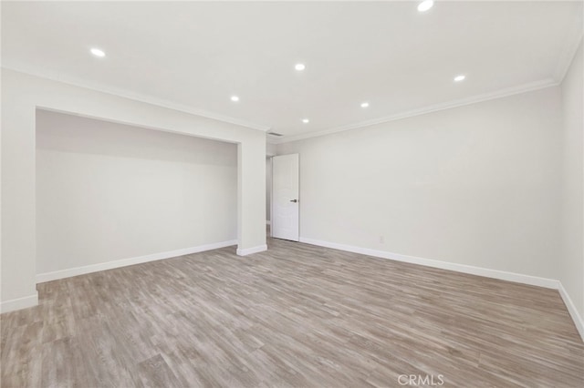 spare room featuring light wood-style floors, baseboards, crown molding, and recessed lighting