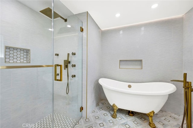 full bathroom featuring a freestanding tub, tile patterned floors, tile walls, and a stall shower