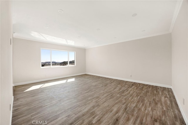 spare room with crown molding, baseboards, and wood finished floors