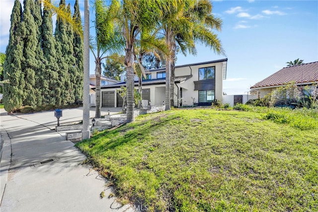 view of front of home featuring a garage, a front yard, and stucco siding