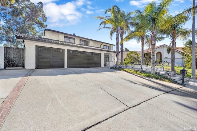 view of front facade featuring concrete driveway, a tiled roof, an attached garage, and stucco siding