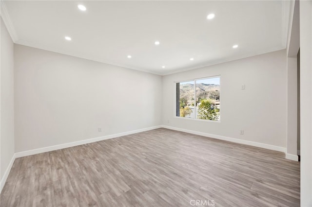 empty room featuring ornamental molding, recessed lighting, wood finished floors, and baseboards