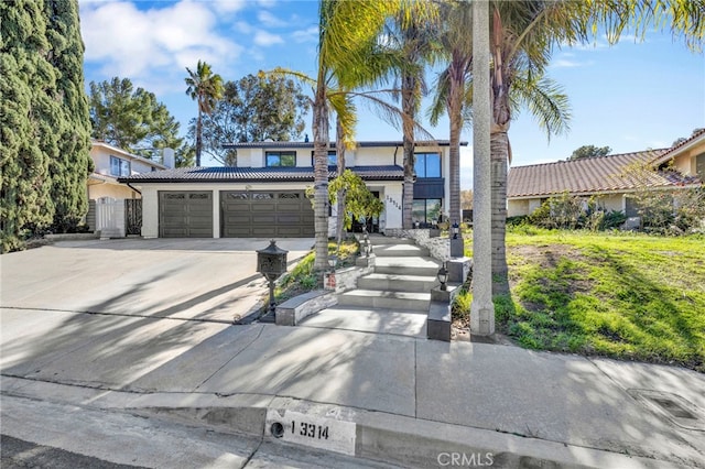 view of front of property featuring an attached garage, driveway, a tile roof, and stucco siding