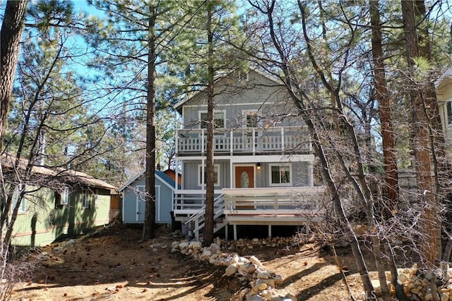 view of front of home with a storage shed, an outbuilding, and a balcony