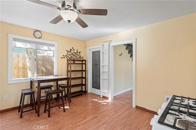 dining space with light wood-style floors, baseboards, and a ceiling fan