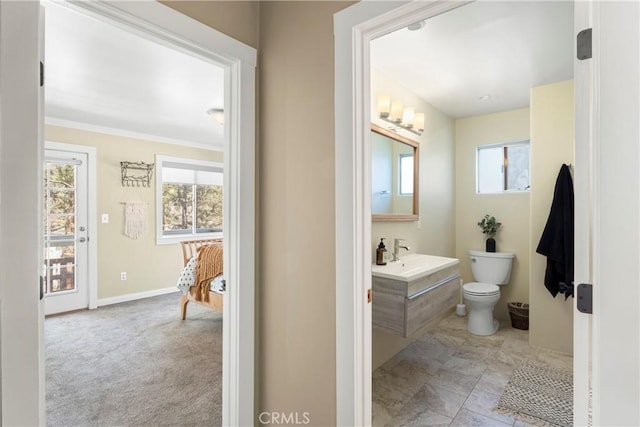 bathroom with a healthy amount of sunlight, baseboards, toilet, and vanity