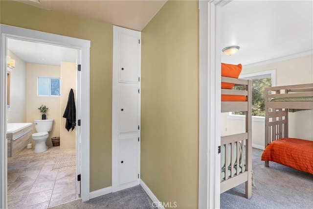 interior space with light carpet, ensuite bath, baseboards, and light tile patterned floors