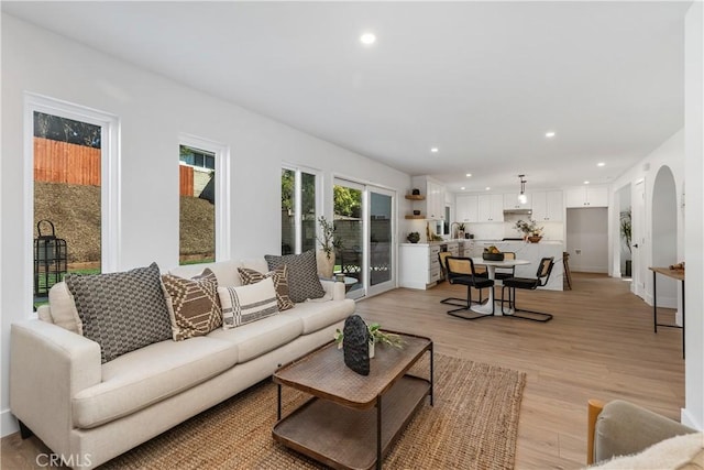 living room featuring arched walkways, recessed lighting, and light wood-style floors