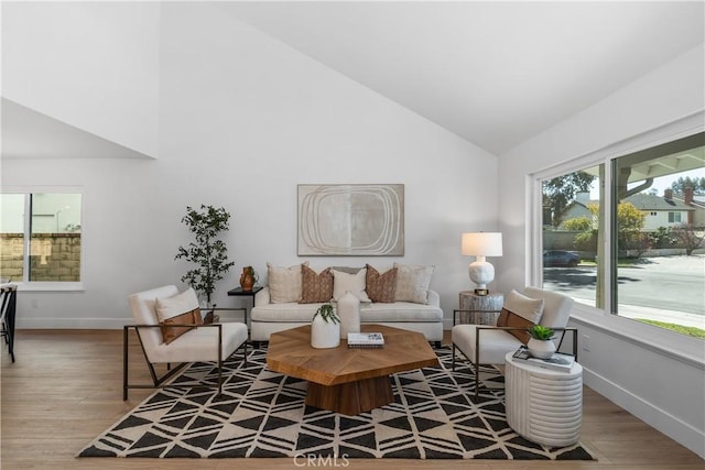 living area with baseboards, high vaulted ceiling, and wood finished floors