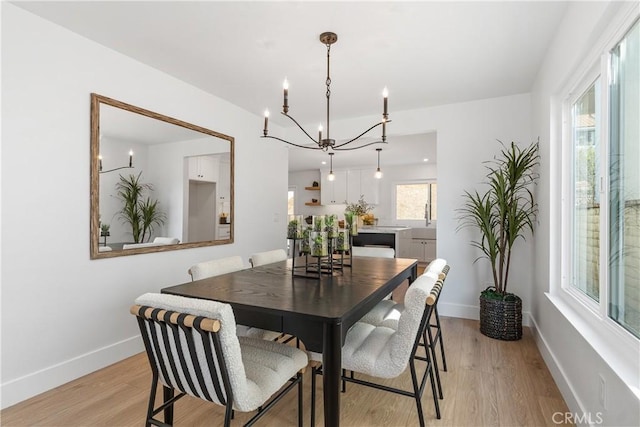 dining room with baseboards, a chandelier, and light wood-style floors