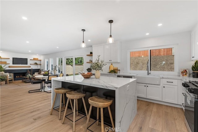 kitchen with black range with gas stovetop, a sink, and white cabinetry