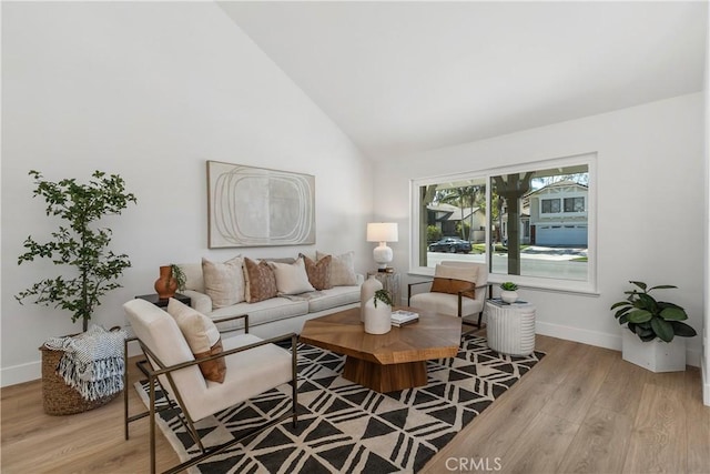 living area with high vaulted ceiling, baseboards, and wood finished floors