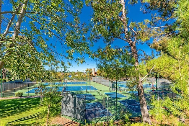 view of sport court with fence and a lawn