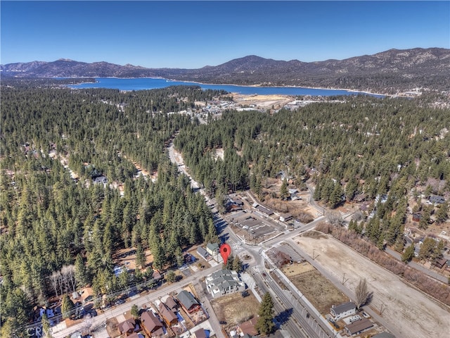 aerial view with a wooded view and a water and mountain view