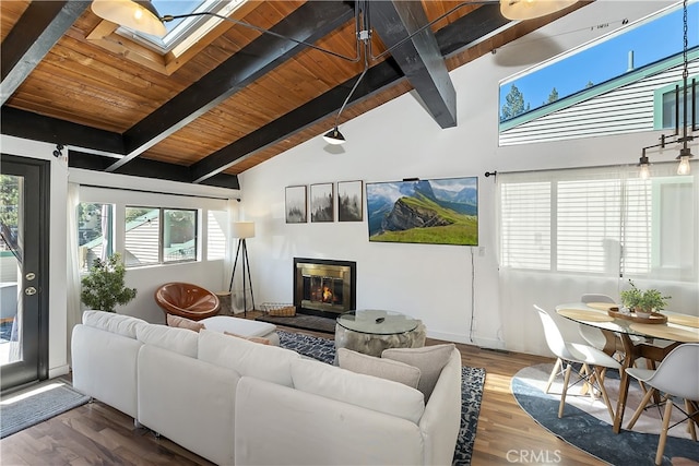 living room with lofted ceiling with skylight, a glass covered fireplace, wooden ceiling, and wood finished floors