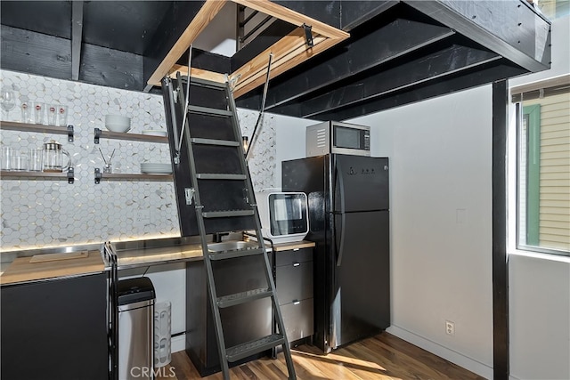 kitchen featuring stainless steel microwave, wood finished floors, freestanding refrigerator, open shelves, and backsplash