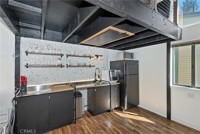 kitchen with dark wood-style flooring, open shelves, stainless steel countertops, freestanding refrigerator, and a sink