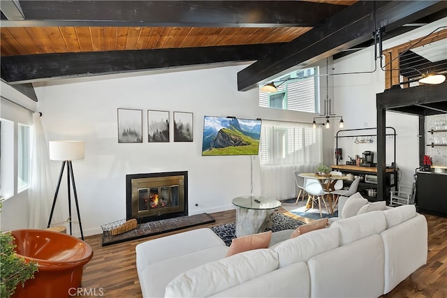 living area with baseboards, a glass covered fireplace, wood ceiling, wood finished floors, and vaulted ceiling with beams