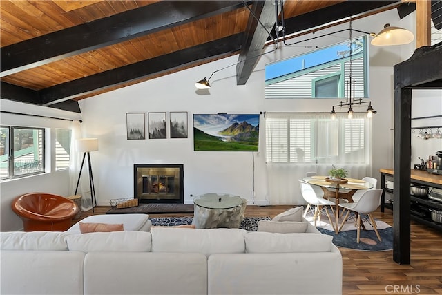 living room with lofted ceiling with beams, wood finished floors, a glass covered fireplace, and wood ceiling