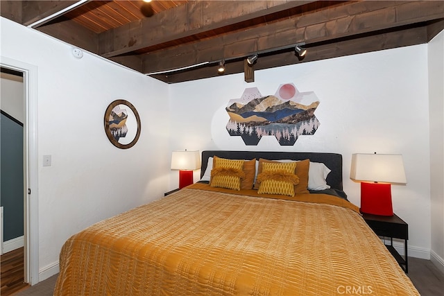 bedroom with baseboards, beamed ceiling, and track lighting