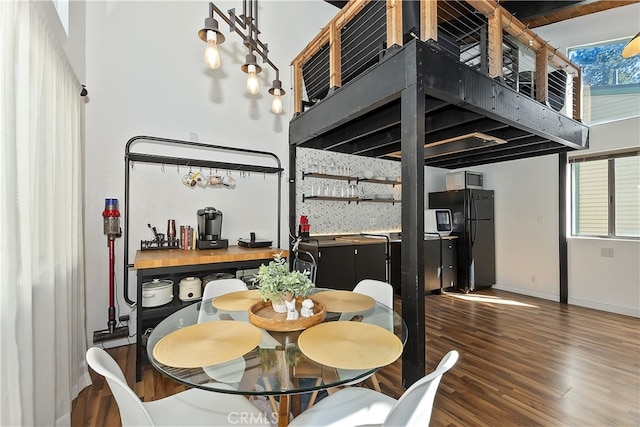 dining space with a high ceiling, baseboards, and wood finished floors