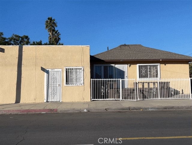 exterior space featuring roof with shingles, fence, and stucco siding