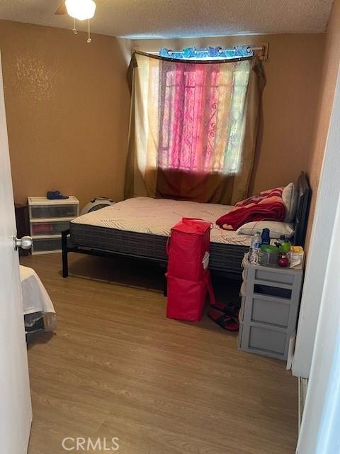 bedroom with a textured ceiling and wood finished floors