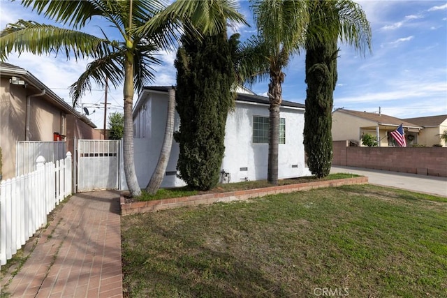 view of home's exterior featuring crawl space, fence, a lawn, and stucco siding