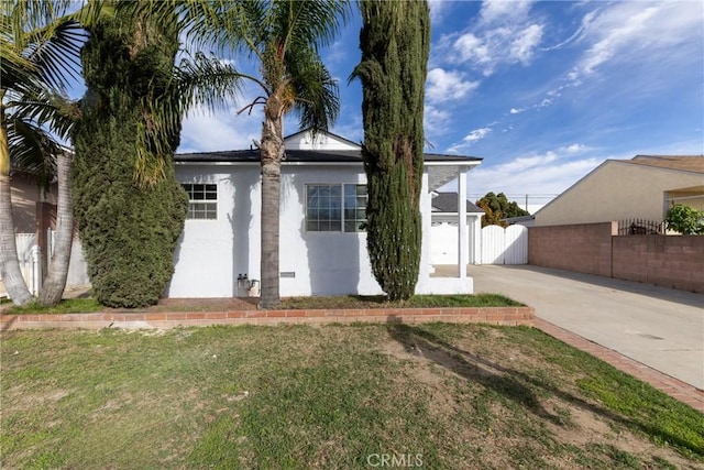 exterior space with a gate, fence, a front lawn, and stucco siding