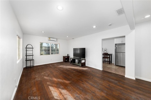 unfurnished living room featuring baseboards, hardwood / wood-style floors, visible vents, and recessed lighting