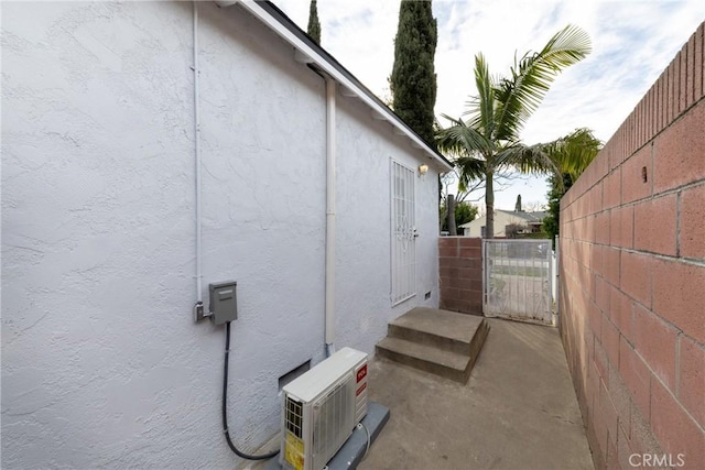 view of side of home featuring a gate, fence, and stucco siding