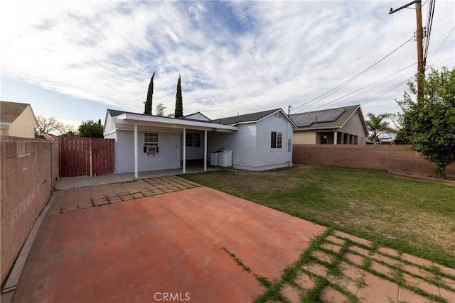 rear view of house featuring a patio area, a yard, a fenced backyard, and stucco siding