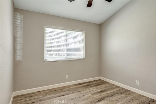 spare room with light wood-style floors, lofted ceiling, baseboards, and a ceiling fan