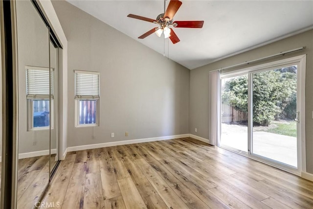 unfurnished room with lofted ceiling, light wood-style flooring, baseboards, and a ceiling fan