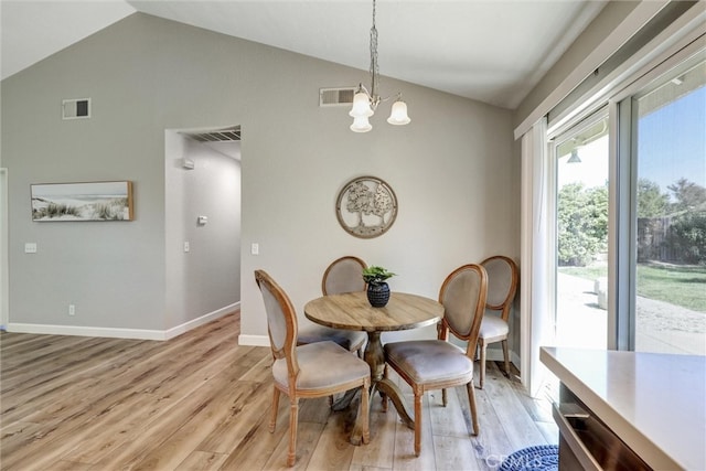 dining room featuring vaulted ceiling, light wood-style flooring, and visible vents