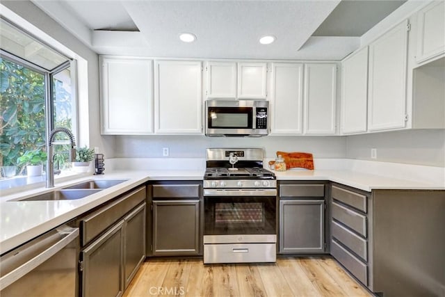 kitchen with recessed lighting, a sink, light wood-style floors, light countertops, and appliances with stainless steel finishes